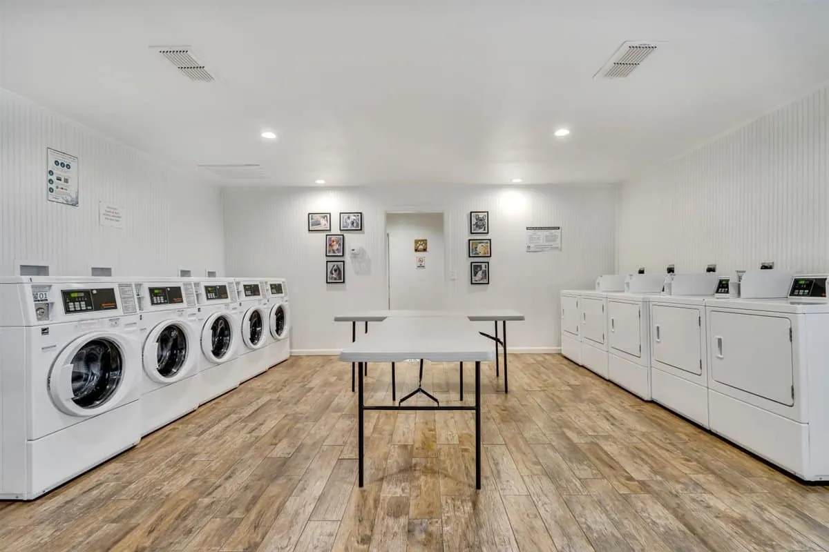 Five washers and dryers, a folding table, and hanging racks in the Laundromutt laundry room at Waggin' Tail Ranch RV Resort, Pilot Point, TX