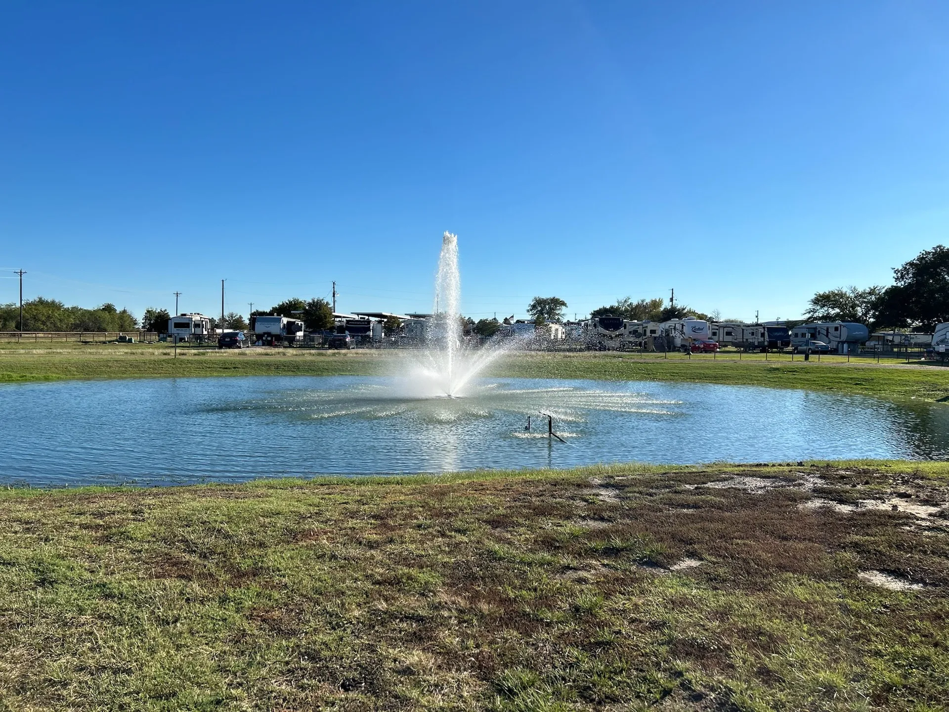 The pond fountain with RV sites beyond · Waggin' Tail Ranch RV Resort, Pilot Point, Texas