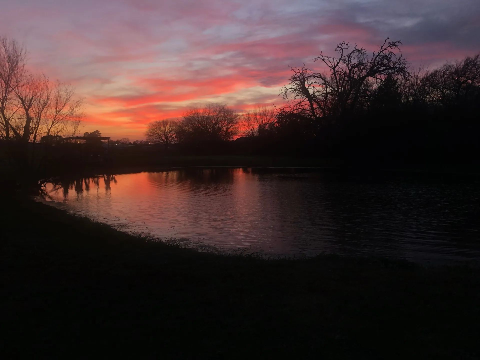 A fiery sunset over the pond at Waggin' Tail Ranch RV Resort in Pilot Point, TX, the quiet end of a couples weekend