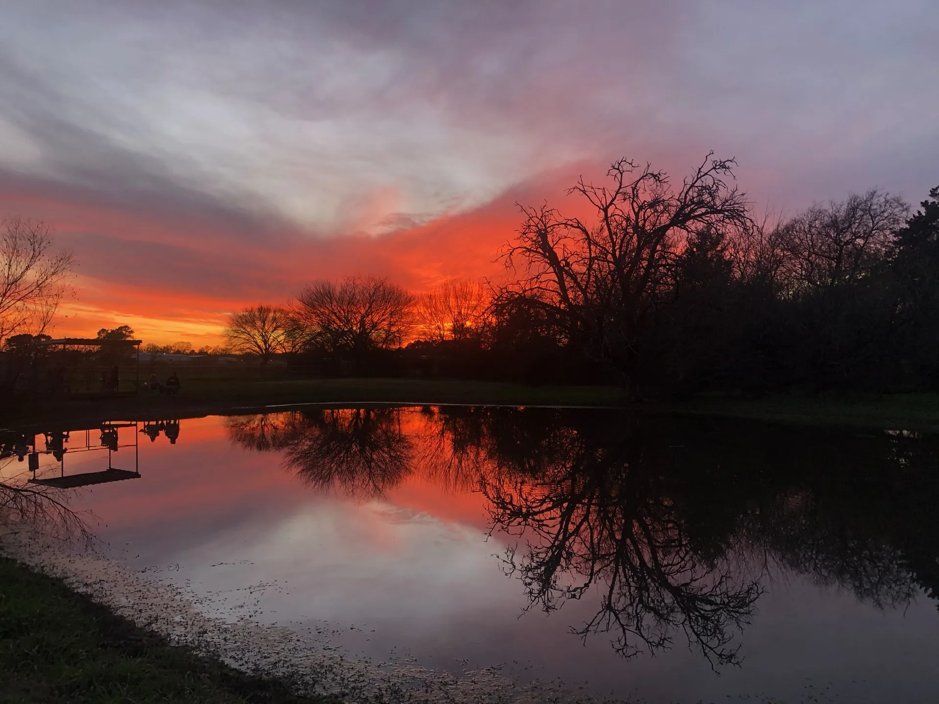 A fiery sunset over the pond at Waggin' Tail Ranch RV Resort in Pilot Point, TX, 52 miles north of Dallas
