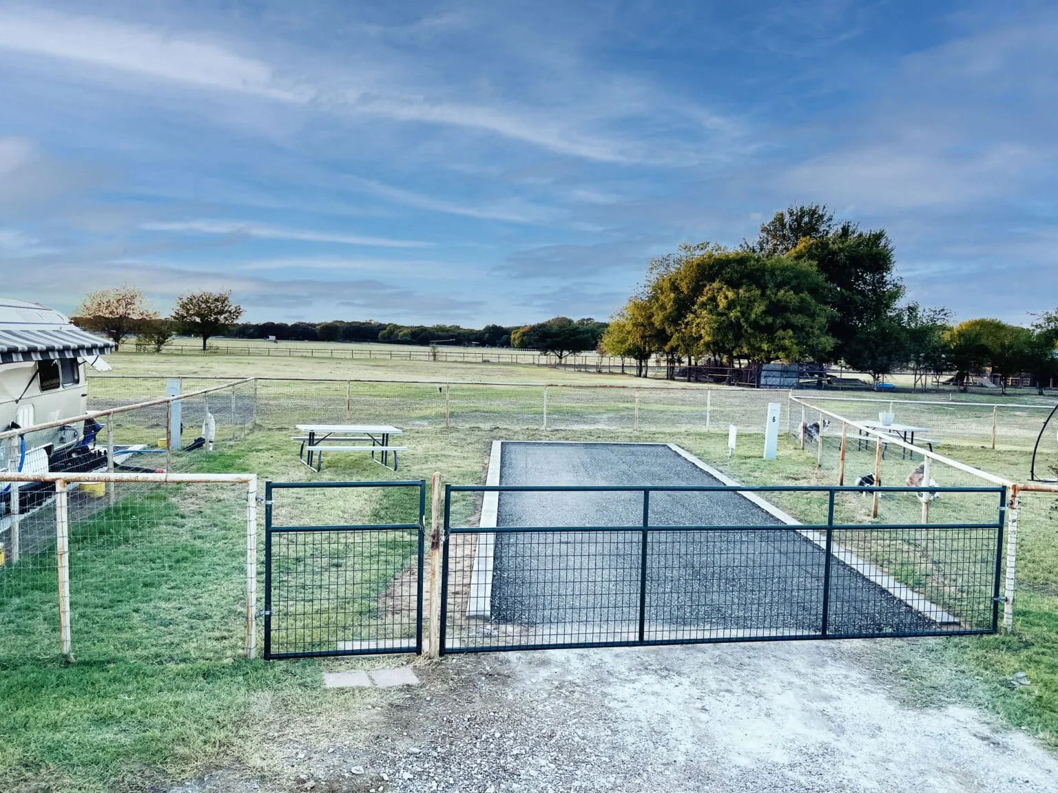 A fenced RV site with drive gate and picnic table at Waggin' Tail Ranch RV Resort in Pilot Point, TX