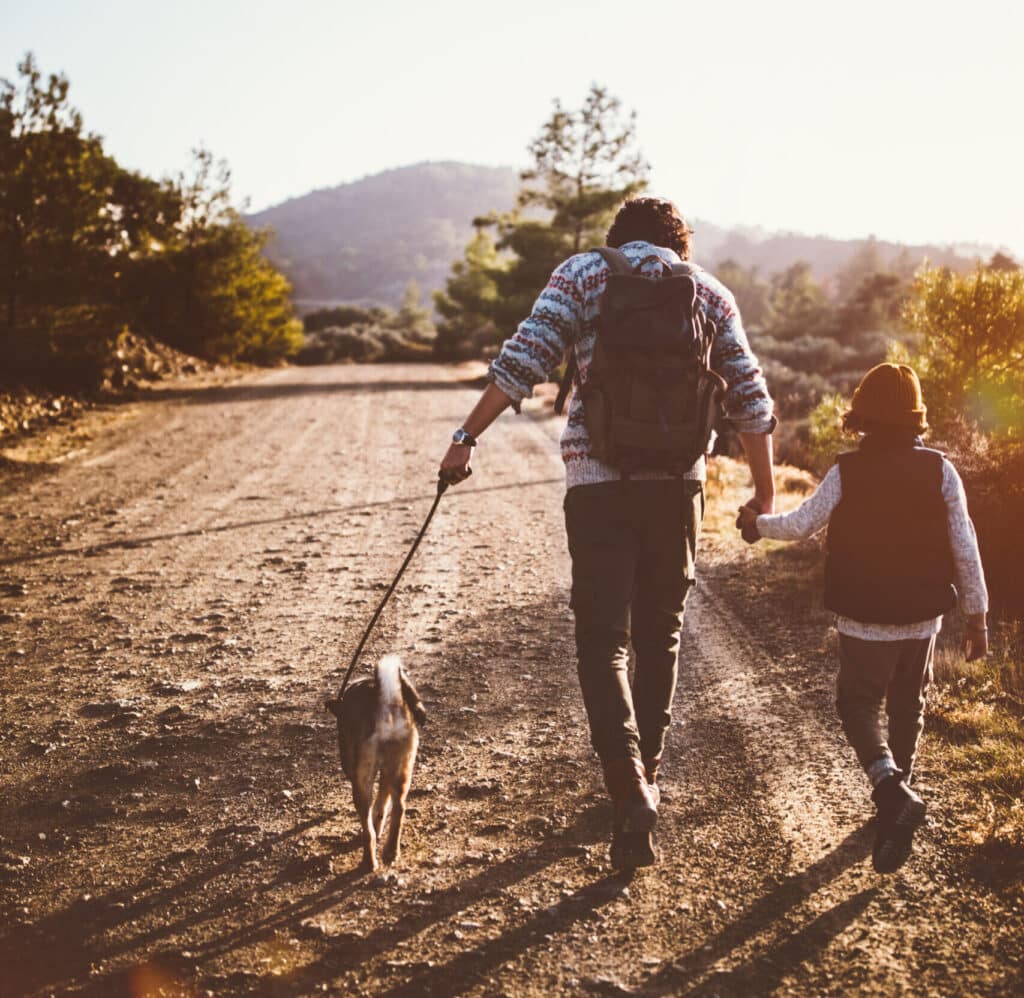 Image of a father, son, and dog hiking and camping